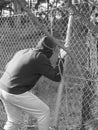 Person crawling through a fence opening with hand clinging to a steel wire , black and white