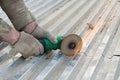 A person cuts a sheet of roofing iron with a special electric tool.Angle grinder for metal cutting. Sparks fly. Gloved hand. Royalty Free Stock Photo