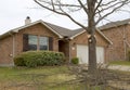 A person cutting branches with cordless pole saw in front of house