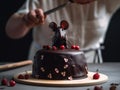 A person cutting a chocolate cake with a chocolate mouse on top, AI