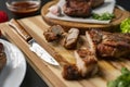 person cutting cooked or grilled beef steak with a knife on a wooden boards