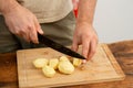 A person cutting peeled potatoes on a bamboo cutting board, meal preparation concept.