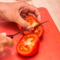 A person cutting a piece of food. Sliced tomato. Royalty Free Stock Photo