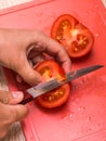 A person cutting a piece of food. Sliced tomato. Royalty Free Stock Photo