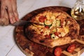 Person delicately slicing pizza on a cutting board with a sharp knife Royalty Free Stock Photo