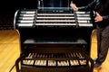 A person demonstrates an organ - musical instrument, keyboard, buttons and pedals in a contemporary music hall