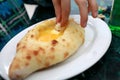 Person dipping adjarian khachapuri into yolk egg