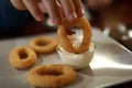 Person dipping breaded squid ring into sauce