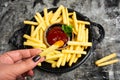 Person dipping French fries and tomato sauce