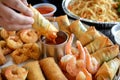 a person dipping a spring roll into sauce on a table with egg rolls and fried shrimp Royalty Free Stock Photo