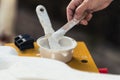 Person dipping white paste with a spatula in a workshop Royalty Free Stock Photo