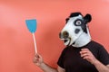 Person disguised as a cow mask with a fly swatting shovel