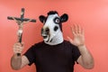 Person disguised in a cow mask holding a crucifix pretending to perform an exorcism Royalty Free Stock Photo