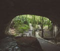 A person in the distance waving under an open cave in nature