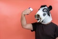 Person dressed in a latex cow mask taking her temperature with an infrared thermometer