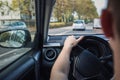 Person driving his car on the city street, close up of person hands on the steering wheel Royalty Free Stock Photo