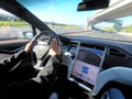 Person driving a Tesla plug-in electric car Model X on a motorway