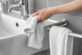 person drying hands with towel on rail next to sink