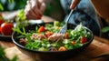 Person eating healthy salmon salad with fresh vegetables