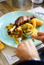 A person eating roasted goose leg with cabbage papardelle pasta and quince compote