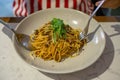 Person eating Spaghetti Bolognese topped with Grated Cheese and Arugula with Fork and Spoon in a Restaurant Royalty Free Stock Photo