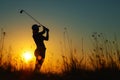 A person energetically swings a golf club against a backdrop of a stunning sunset, A lady golfer preparing for a swing against Royalty Free Stock Photo