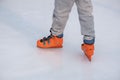 Person is enjoying a day of ice skating on a frozen rink wearing a pair of bright orange skates.