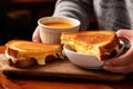 person enjoying a grilled cheese sandwich with soup