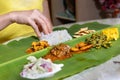 Person enjoying Indian banana leaf rice consisting mutton curry, squid, prawn, papadam and various vegetables Royalty Free Stock Photo