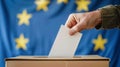 A person entering a vote into a ballot box European Union flag in background. European elections Royalty Free Stock Photo