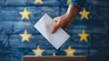 A person entering a vote into a ballot box European Union flag in background. European elections Royalty Free Stock Photo