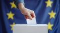 A person entering a vote into a ballot box European Union flag in background. European elections Royalty Free Stock Photo