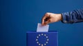 A person entering a vote into a ballot box European Union flag in background. European elections Royalty Free Stock Photo