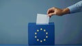 A person entering a vote into a ballot box European Union flag in background. European elections Royalty Free Stock Photo