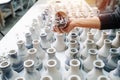 Person examining a vase, holding it over long rows of freshly made vases.