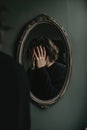 Person expressing self-image concerns while covering their face in front of a mirror in minimalistic setting Royalty Free Stock Photo