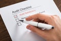 Person Filling Audit Checklist Form At Desk