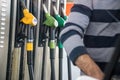 Person filling the fuel tank, highlighting the hoses of the different petroleum products that are in the background. Royalty Free Stock Photo