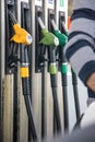 Person filling the fuel tank, highlighting the hoses of the different petroleum products that are in the background. Royalty Free Stock Photo