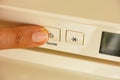 Person finger pressing an on off button on a beige fridge Royalty Free Stock Photo