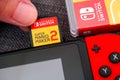 Person fingers inserting Super Mario Maker 2 video game cartridge into the Nintendo Switch video game console