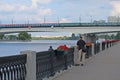 Person fishing in the river, metro bridge with train over the river