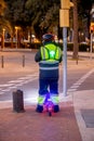 Person with flashing arrow on his back, riding scooted on the street in Barcelona on sunset