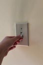 Person flipping light switch on a wall