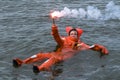 Person floating in survival suit holding red handflare
