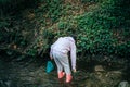 Person in the forest. Asian child fishing with a net to discover nature. One girl in pink playing in a stream Royalty Free Stock Photo