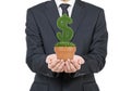 A person in formal suit holds a flowerpot with grass green dollar sign.