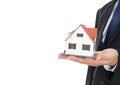 A person in formal wear holds a small house model in his hand