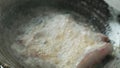 A person frying marinated fish fillets in a pan with boiling oil til it`s well