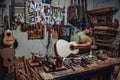 a person working on a guitar in a garage surrounded by various guitars